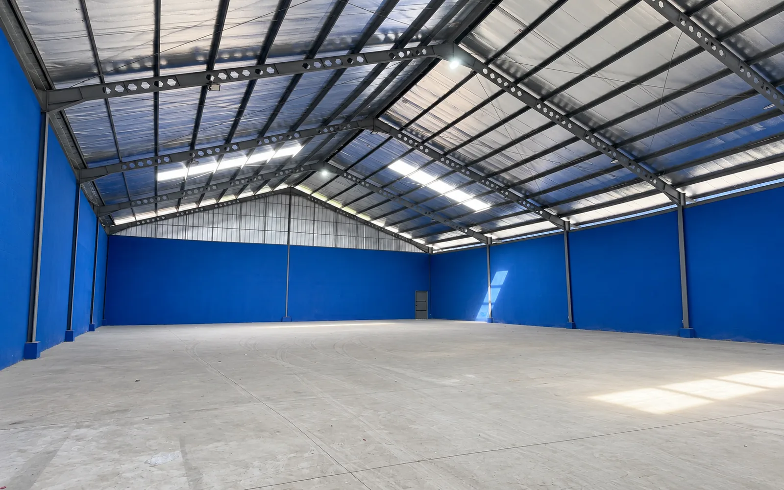 Visualisasi interior Gudang Pasir Angin dengan rangka baja, dinding biru, dan lantai beton